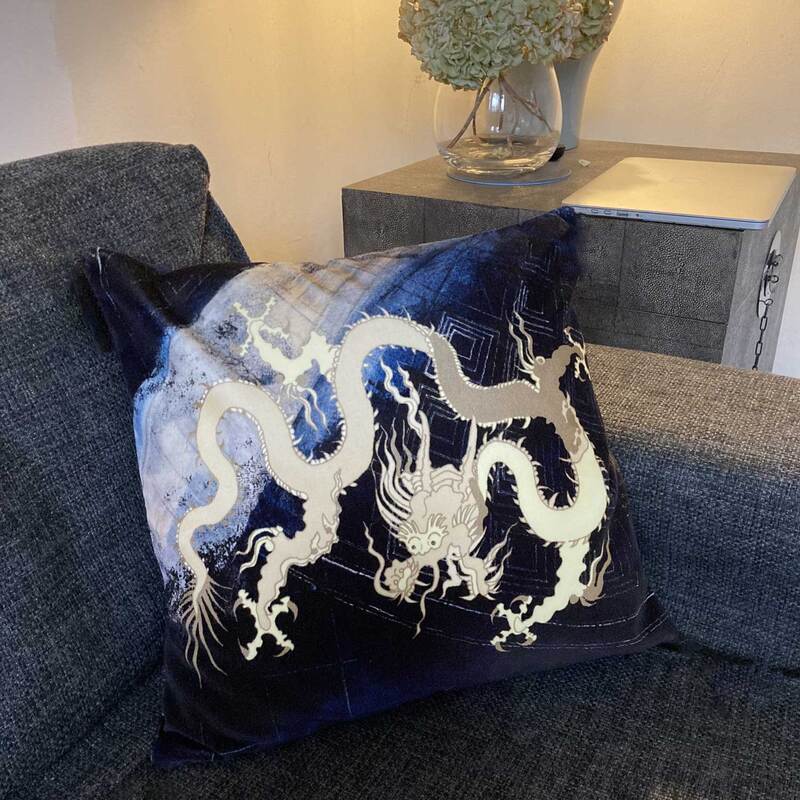 Velvet cushion on sofa with golden dragon on blue background